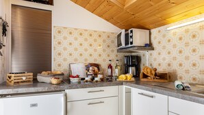 Una cocina con armarios blancos, un microondas y un techo de madera.