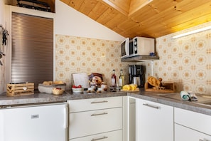 A kitchen with white cabinets, a microwave, and a wooden ceiling.