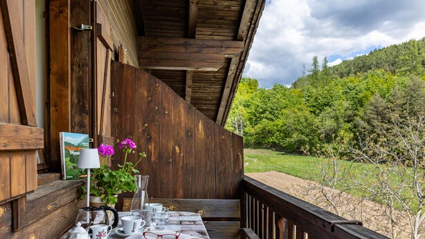 Una terraza de madera con una mesa dispuesta para tomar té, un libro y una lámpara.