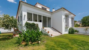 Une maison blanche à deux étages, dotée d’un porche à l’avant, d’un escalier et d’une pelouse bien entretenue.