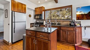 Una cocina con gabinetes de madera, un refrigerador de acero inoxidable, un microondas y una estufa.
