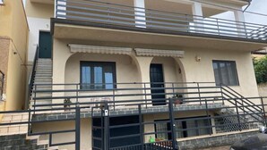 A two-story building with a balcony, a staircase, and a gated entrance.
