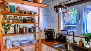 A kitchen with wooden shelves holding jars, pots, and a coffee maker.