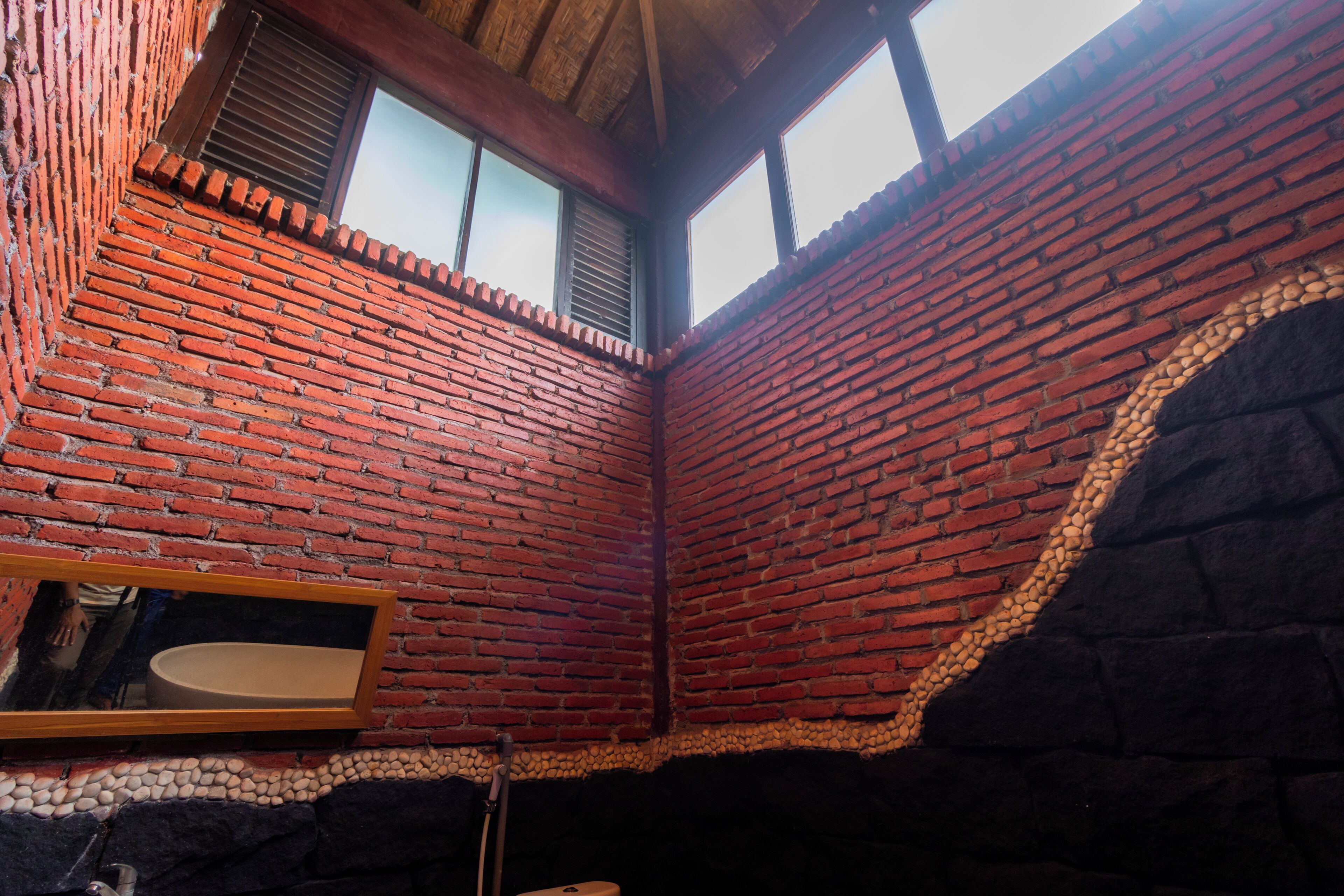 Una habitación con paredes de ladrillo, techo de madera, un espejo y una ventana.