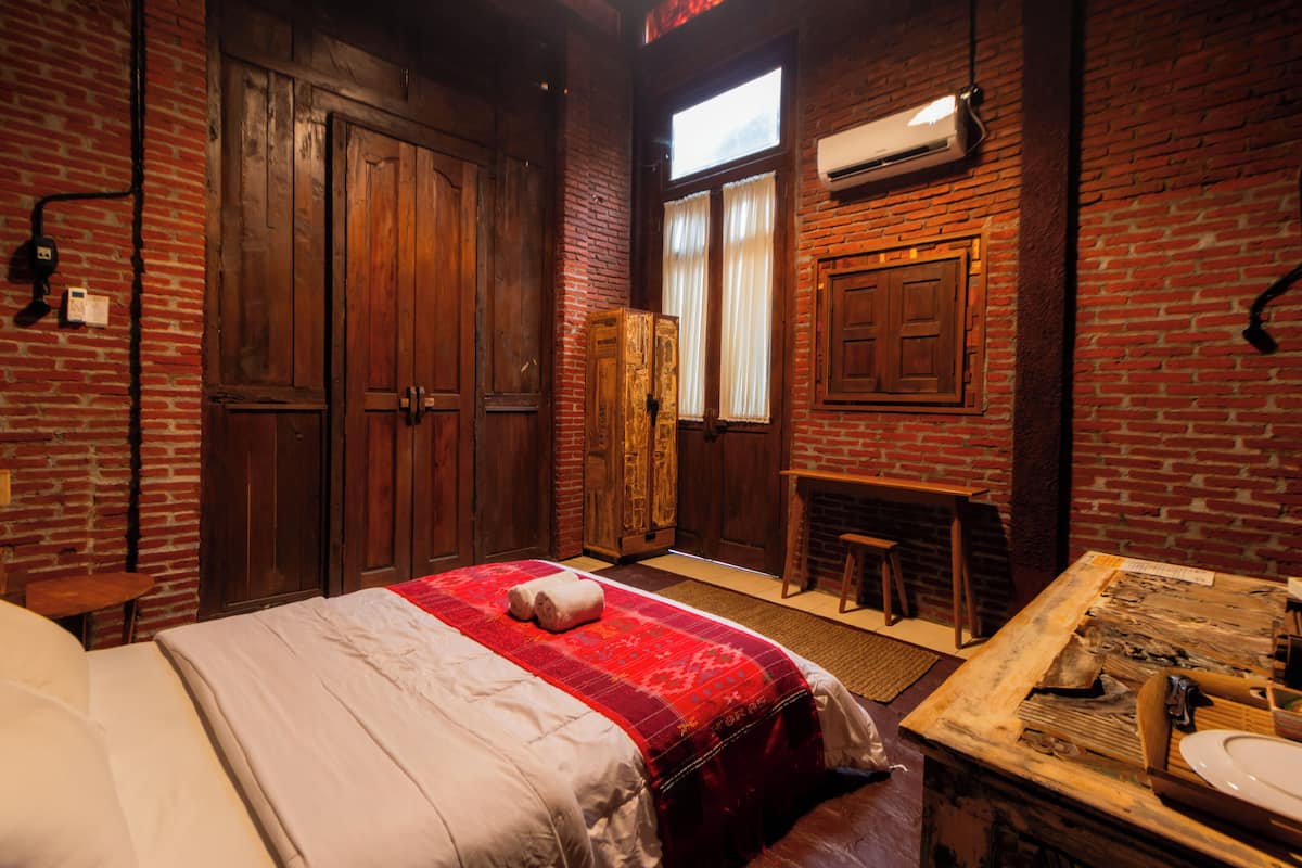 Ein Zimmer mit einem Bett, einem Holztisch, einem Kamin und einer Ziegelwand.