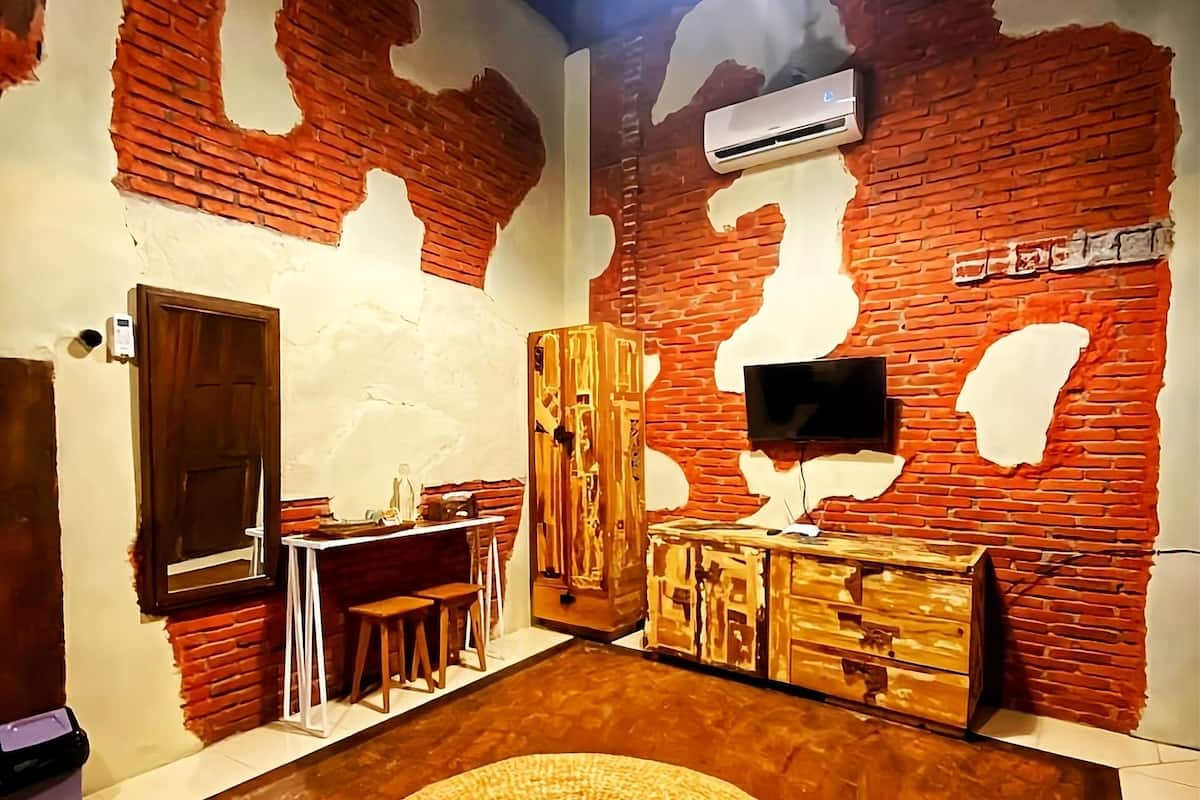 Ein Zimmer mit Backsteinwand, einem runden Teppich, einem Holzschrank und einem an der Wand montierten Fernseher.