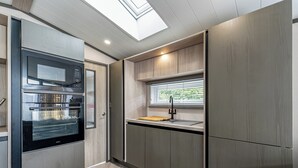 Et moderne køkken med indbyggede apparater, et vindue med persienner og et fiskebensmønstret gulv.