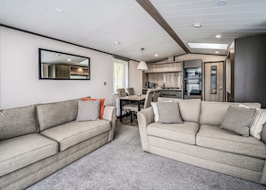 Un interior de autocaravana moderna con dos sofás, una mesa de comedor y una zona de cocina.