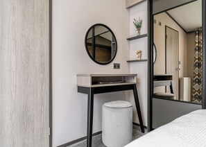 A modern bathroom with a round mirror, a small vanity, a toilet, and a shower area.