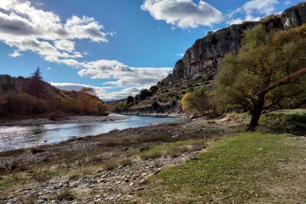 A river flowing through a rocky landscape with a cliff on one side and a tree on the other.