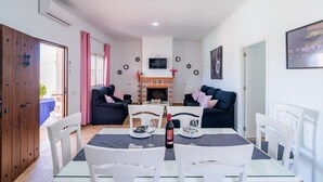 A dining area with a table set for two, a fireplace, and two sofas. - Holiday Home "Casa Rural Rafael" with Private Pool, Private Terraces & Wi-Fi (Lantejuela)