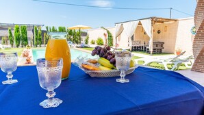 A table with fruit and a glass of orange juice, a pool, and a covered outdoor seating area. - Holiday Home "Casa Rural Rafael" with Private Pool, Private Terraces & Wi-Fi (Lantejuela)