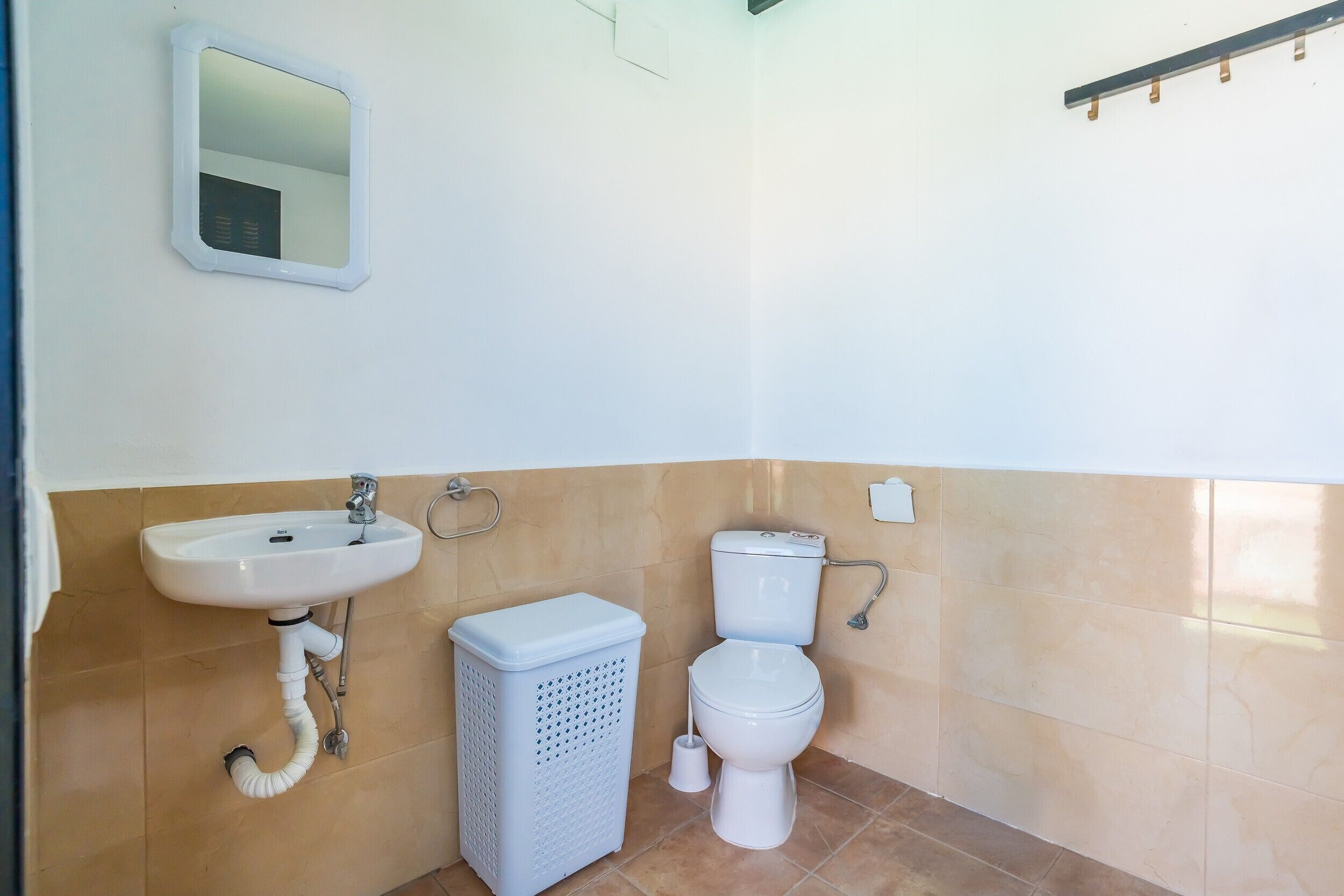 A bathroom with a sink, toilet, and laundry basket.