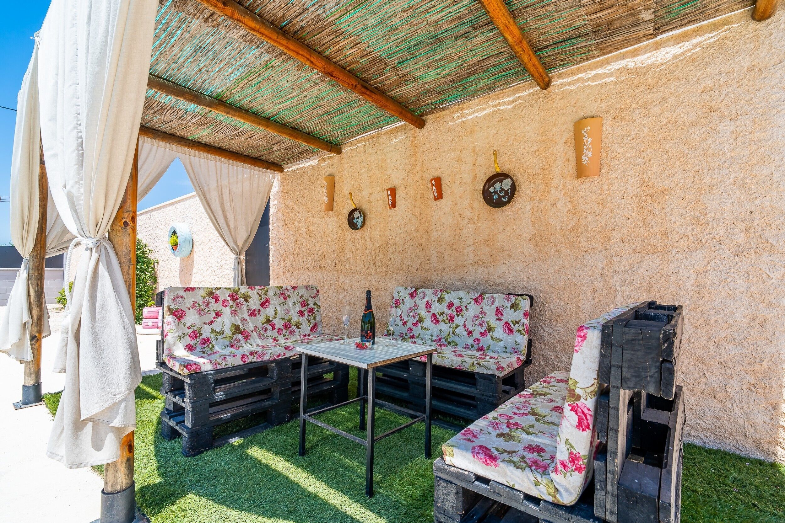 Un espacio al aire libre con mesa, bancos, una botella y un reloj de pared.
