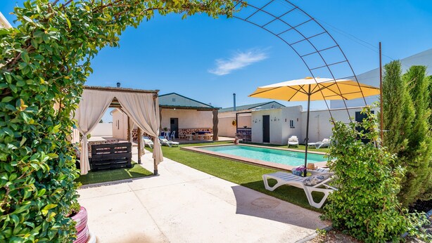 A pool area with lounge chairs, a covered seating area, and a building with a green roof. - Holiday Home "Casa Rural Rafael" with Private Pool, Private Terraces & Wi-Fi (Lantejuela)