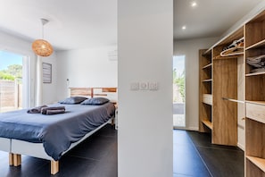Een moderne slaapkamer met een bed, een houten garderobe en een groot raam.