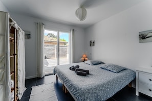 Een slaapkamer met een bed, nachtkastje, lamp, kledingkast en uitzicht.