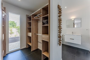 Een moderne badkamer met een wit wastafelmeubilair, een spiegel en een houten plank.