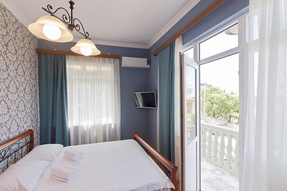 A bedroom with a bed, a TV, and a balcony.