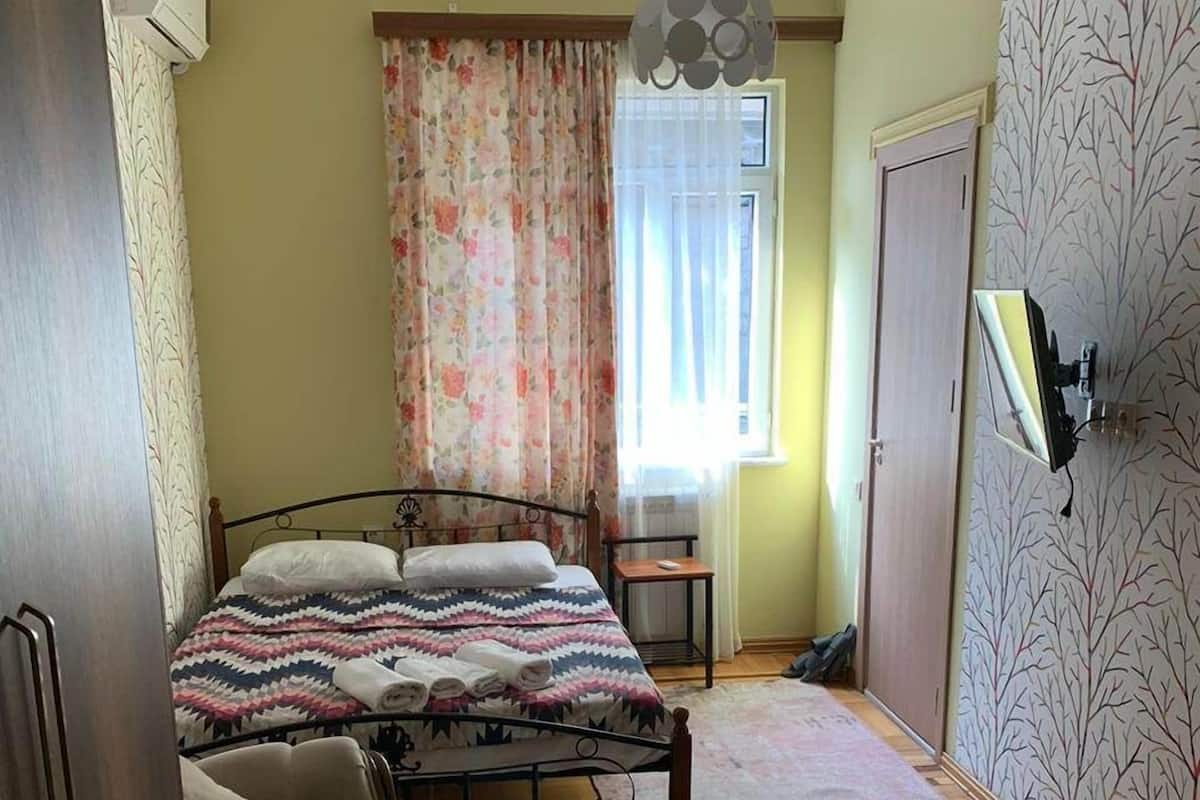 A bedroom with a bed, a chair, a desk, and a wardrobe.
