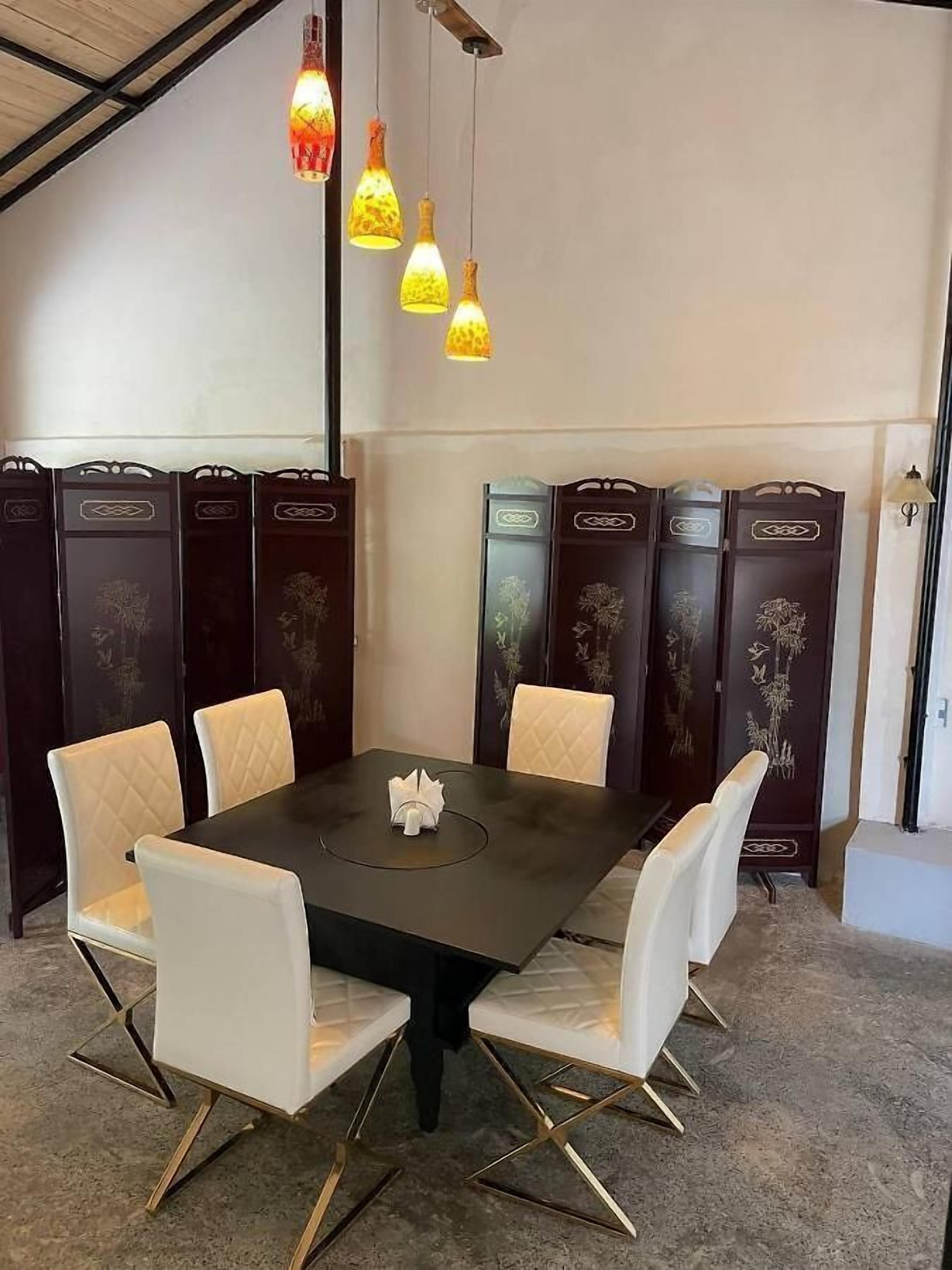 Ein Essbereich mit einem schwarzen Tisch, weißen Sitzgelegenheiten und dekorativen Wandverkleidungen.