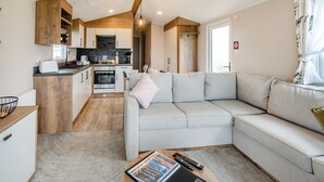 Interior moderno de una casa rodante con cocina, zona de estar con sofá y comedor.