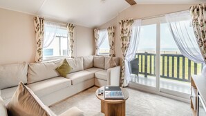 Una habitación con sofá, una mesita y vistas al océano a través de amplias ventanas.