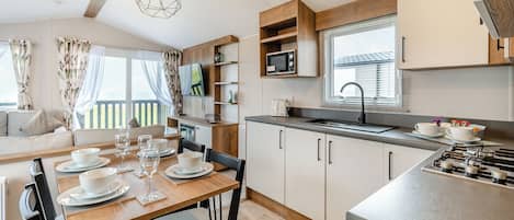 A modern kitchen with a dining area, wooden cabinets, a microwave, and a sink.