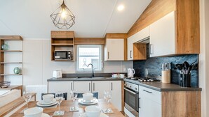 Una cocina moderna con comedor, muebles de madera, horno empotrado y cocina a gas.