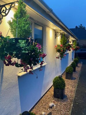 A building with a white exterior, windows with flower boxes, and a gravel pathway. - Toppesfield House (Bude)