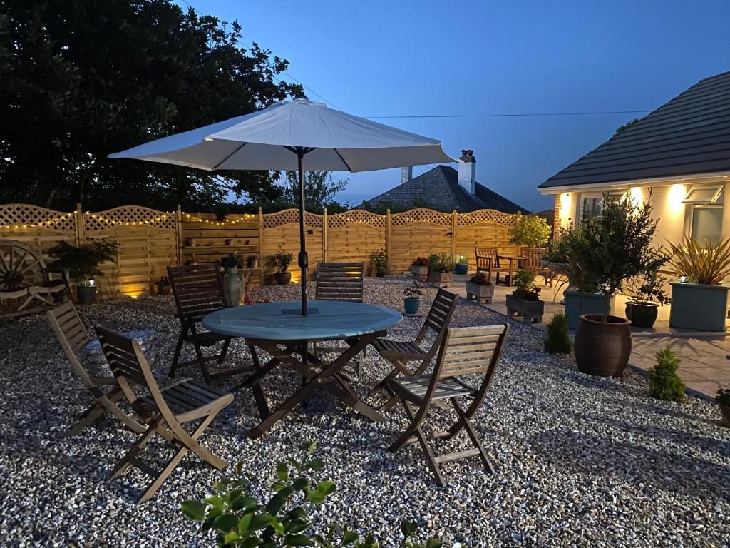 An outdoor patio with a round table, chairs, and a large umbrella.