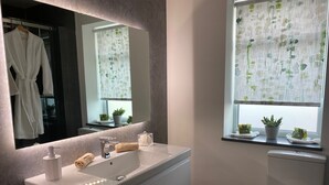 A modern bathroom with a white vanity, a large mirror, and a toilet. - Toppesfield House (Bude)