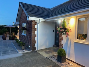 A residential building with a brick facade, a tiled entrance, and a small garden area with potted plants and a bird feeder. - Toppesfield House (Bude)