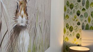 A wall with a large painting of a rabbit and a patterned wallpaper with leaves. - Toppesfield House (Bude)