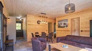 Een houten interieur met een bank, een eettafel, stoelen en een keuken.