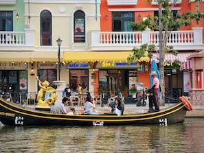 A boat with people on it, a building with a sign for a spa, and a tree in the foreground.