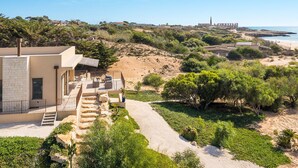 A coastal property with a patio, a staircase leading to the entrance, and a view of the beach and ocean. - Sea view and direct access to the sandy beach (Sampieri)