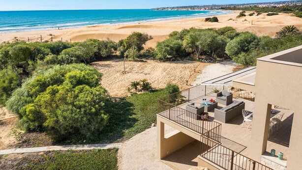 A balcony with outdoor furniture overlooking a beach and ocean. - Sea view and direct access to the sandy beach (Sampieri)