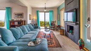 A living room with a sofa, a fireplace, a television, and a view of the outdoors. - Sea view and direct access to the sandy beach (Sampieri)