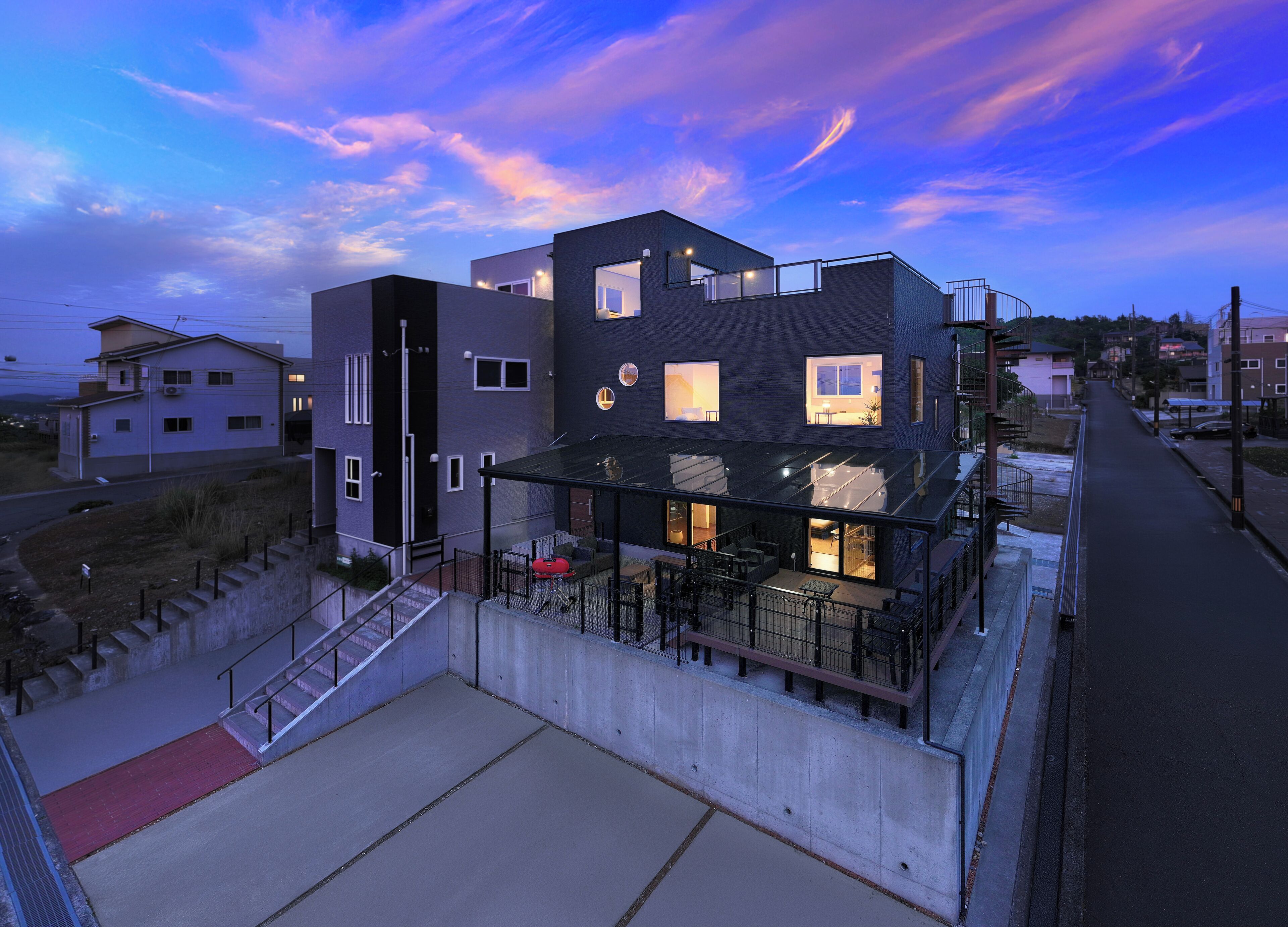 Un edificio moderno de varios pisos con techo plano, ventanas amplias y un espacio al aire libre cubierto para asientos.