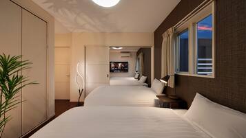 Een hotelkamer met twee bedden, een televisie, een plant en een raam met gordijnen.