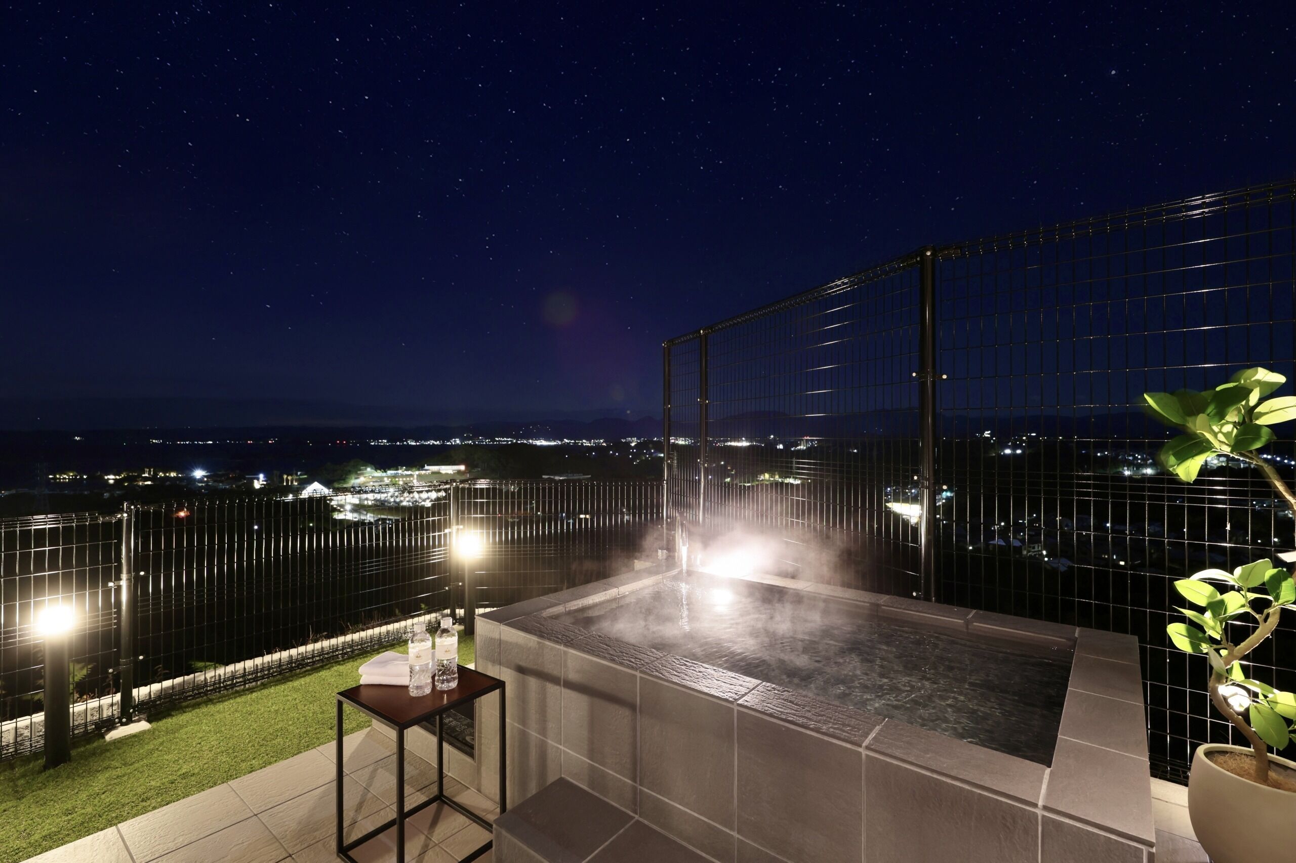 A rooftop jacuzzi with a city view at night.