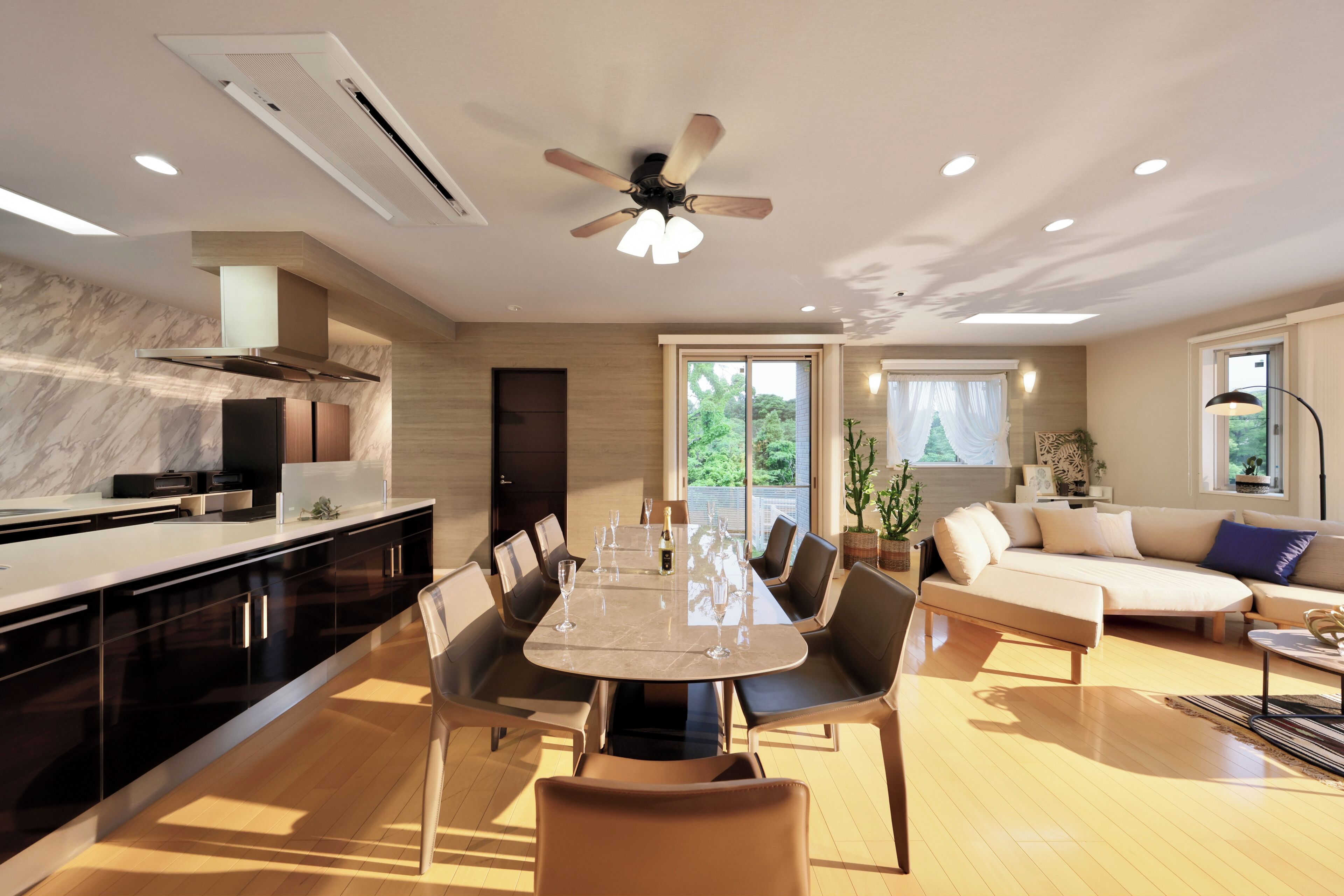 Una cocina moderna con comedor, ventilador de techo y un ventanal grande.