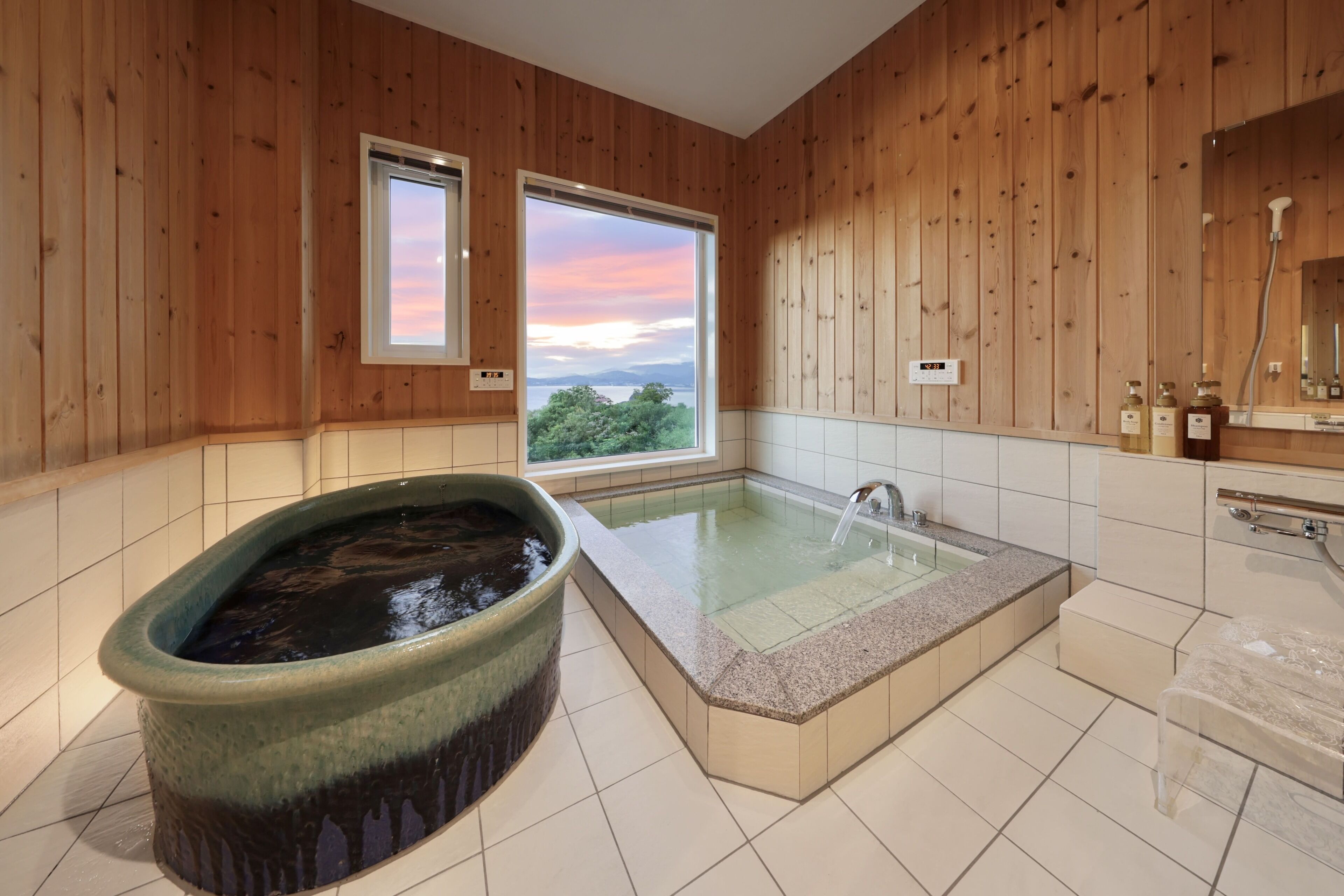 Un baño moderno con una bañera grande, zona de ducha separada y vistas al exterior a través de un amplio ventanal.