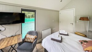 A bedroom with a bed, a chair, a TV, and a view of the water outside. - 1 bedroom accommodation in Halling (Halling)