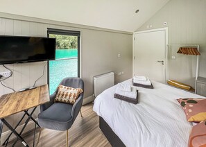 A bedroom with a bed, a chair, a TV, and a view of the water outside. - 1 bedroom accommodation in Halling (Halling)