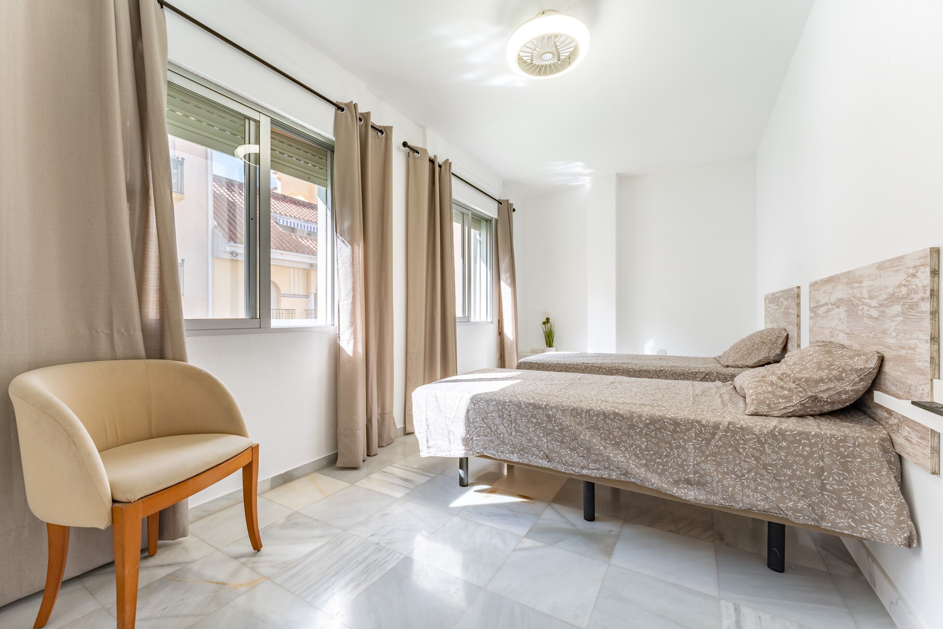 Une chambre à coucher avec un lit, une chaise et une fenêtre avec des rideaux.