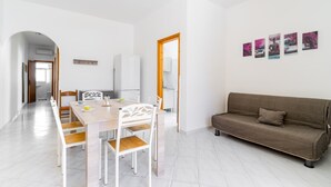 Een moderne woonkamer met een eethoek, een bank en een keuken op de achtergrond.
