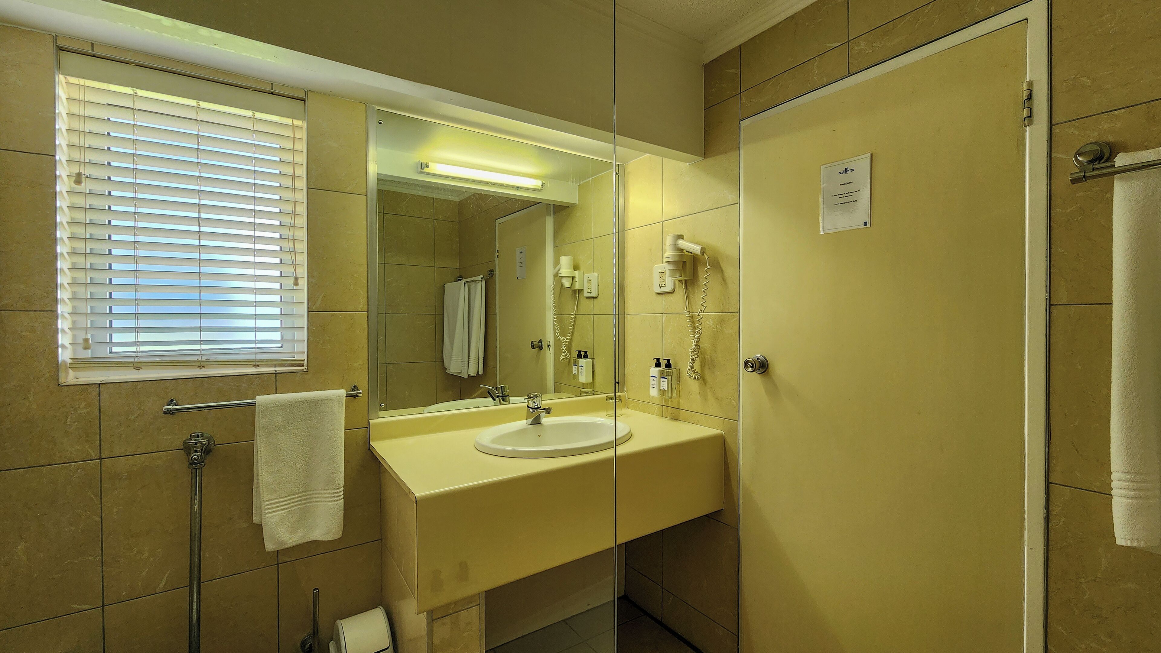A bathroom with a sink, mirror, towel rack, and a shower area.
