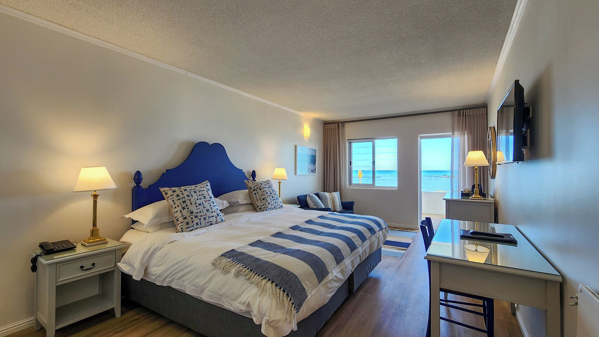 Een hotelkamer met een groot bed, nachtkastjes, een bureau en een televisie.